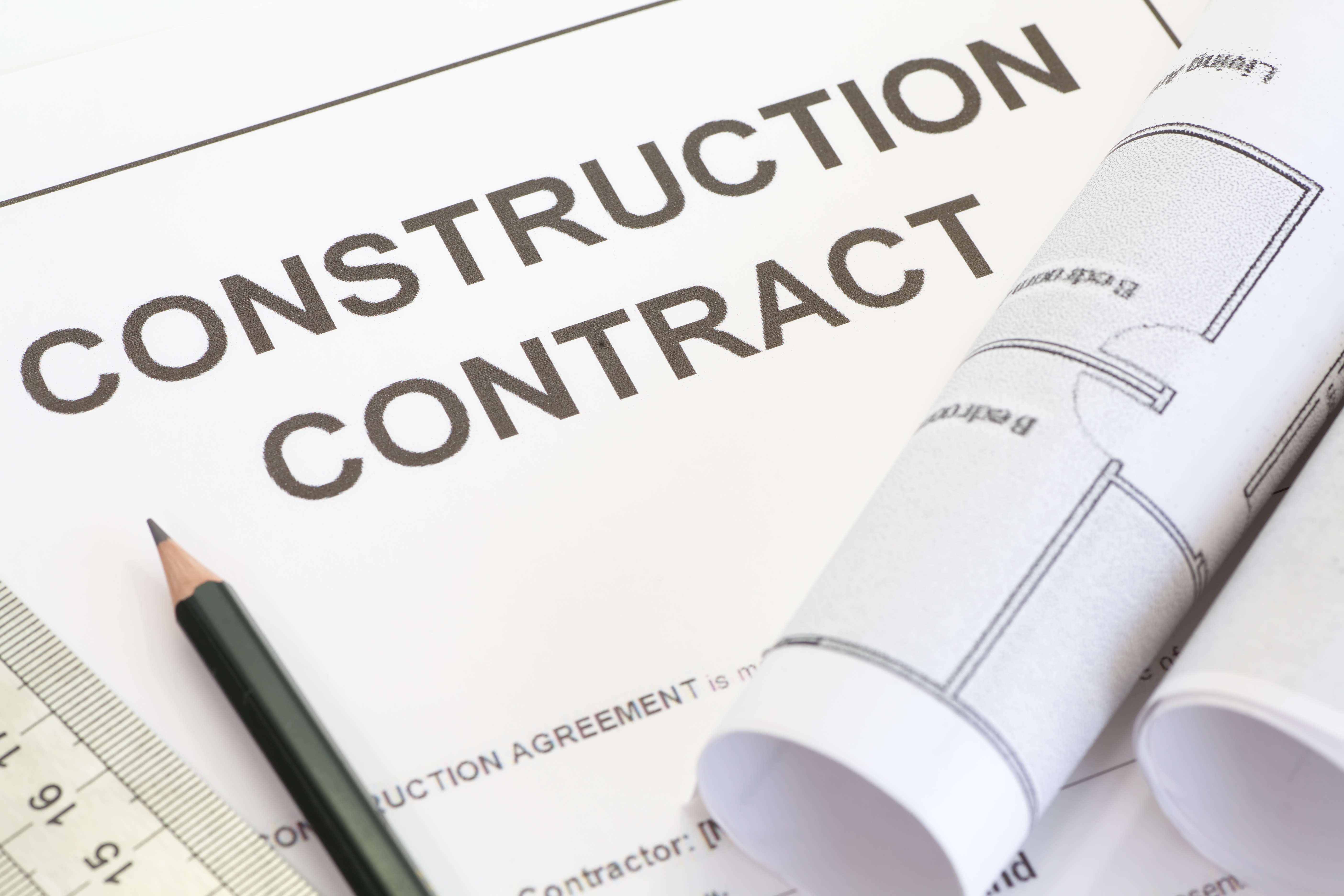 Close - up construction contract with pen and architectural roll